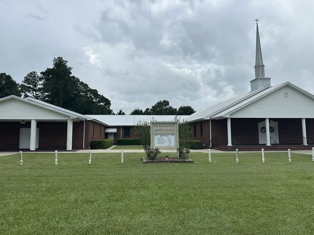 The front of Hacklebarney Baptist Church: red brick with white columns, a white steeple, and the church sign on the lawn